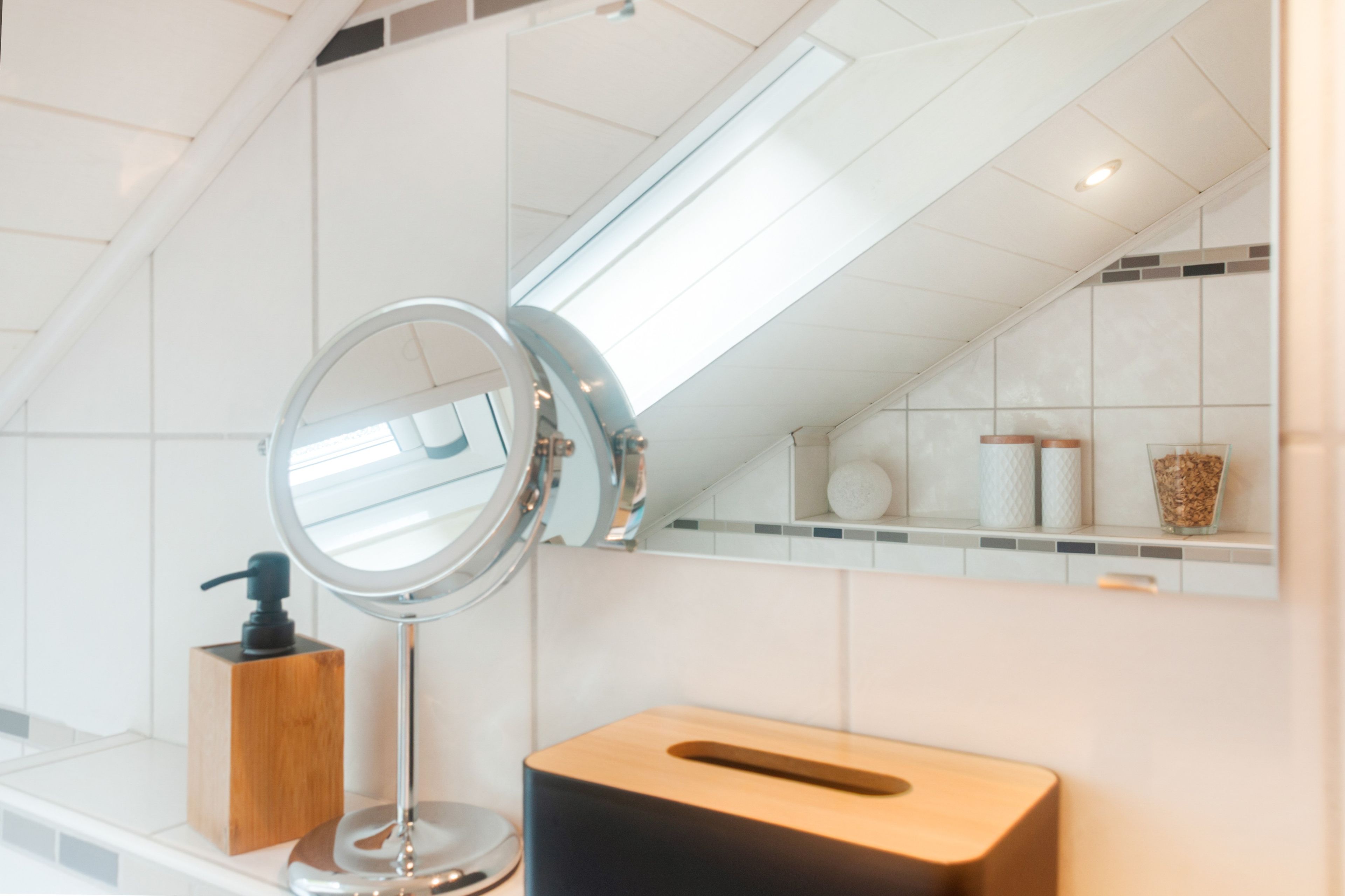 A bathroom with a mirror, a soap dispenser, a towel holder, and a toilet paper holder.