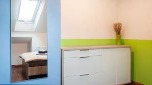 A room with a bed, a cabinet, a radiator, and a window with natural light.