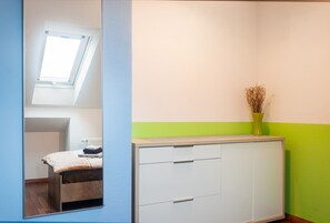 A room with a bed, a cabinet, a radiator, and a window with natural light.