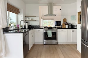 A modern kitchen with white cabinets, a stainless steel range, and a built-in oven. - Cute 2-bedroom Oceanside house in beautiful 55+ Ocean Hills Country Club (Oceanside)