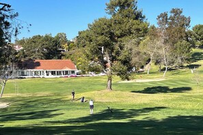 Ein Golfplatz mit Clubhaus, Bäumen und blauem Himmel.