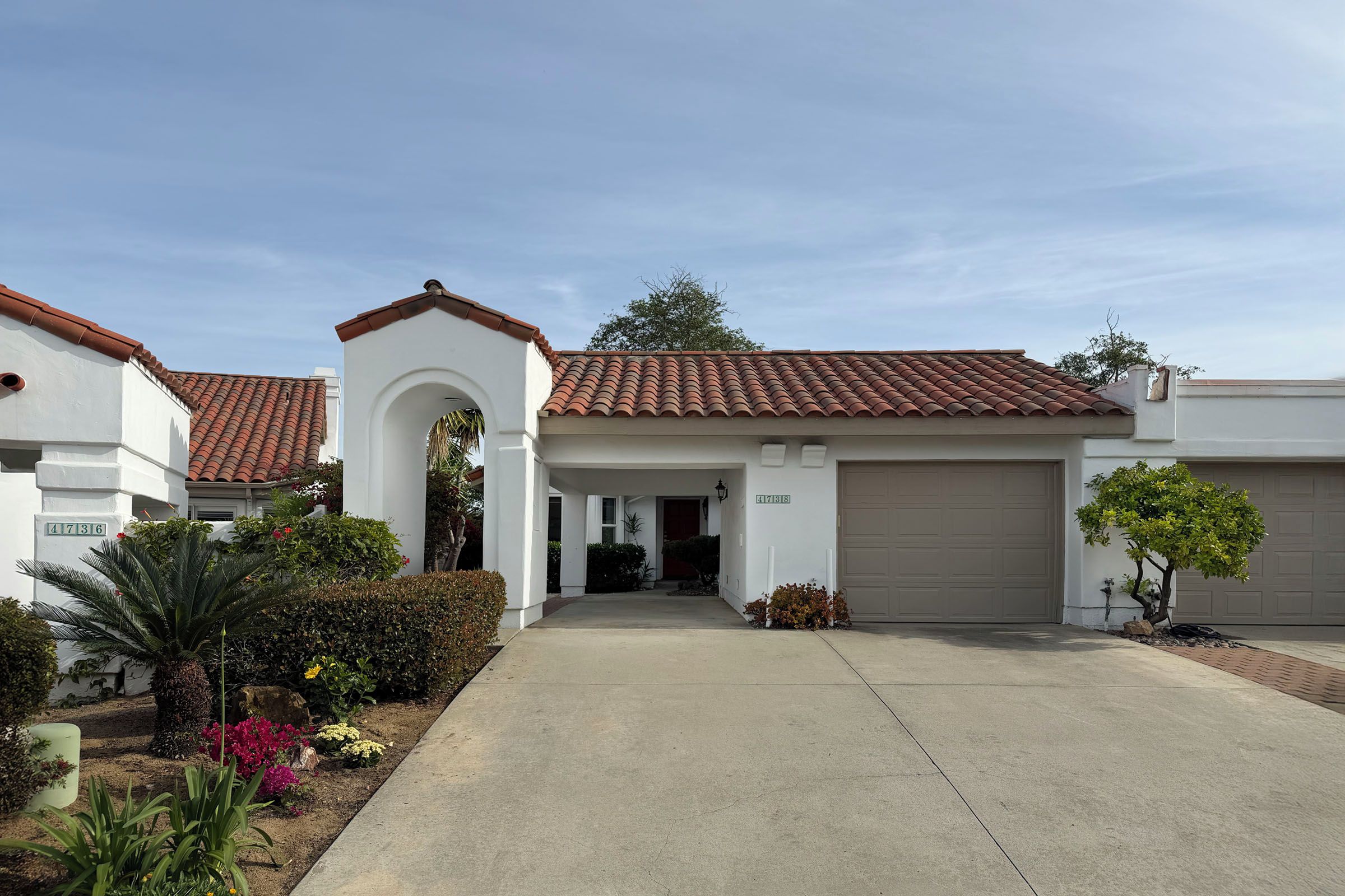 A residential property with a covered driveway, a garage, and a well-maintained garden.