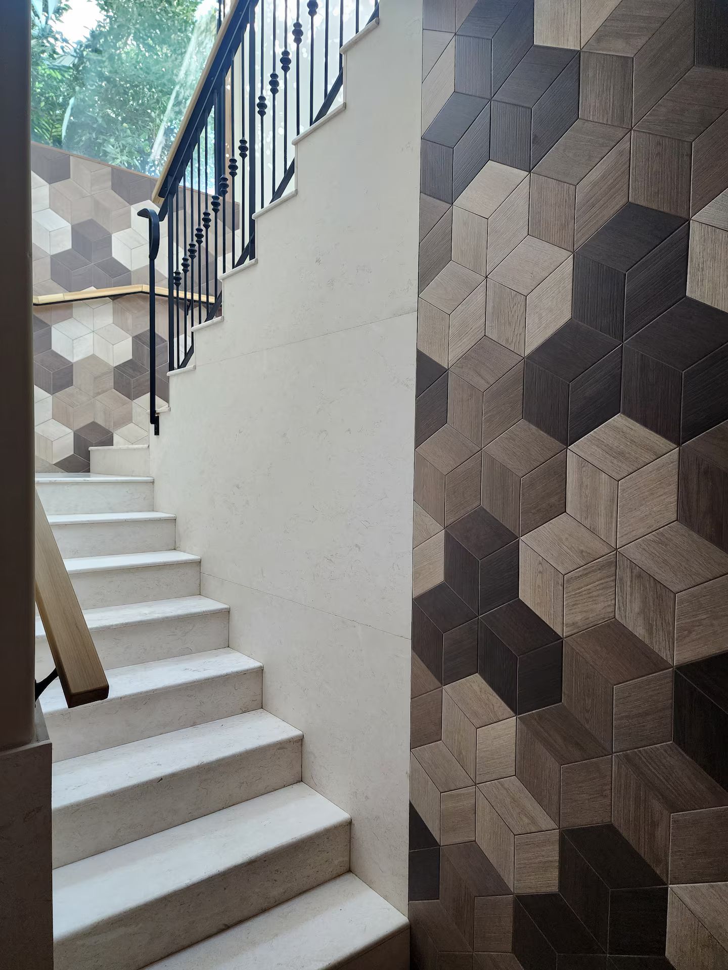 Uma escadaria com uma parede decorada com padrão geométrico de um lado e uma parede lisa do outro.