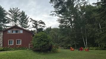 A grassy area with a red building and trees in the background.