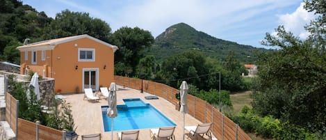 Un bâtiment à deux étages doté d’une piscine, d’un espace extérieur aménagé et offrant une vue sur un paysage montagneux.