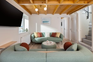 Ein modernes Wohnzimmer mit einer grünen Sofagarnitur, einem Couchtisch und einem an der Wand montierten Flachbildfernseher.