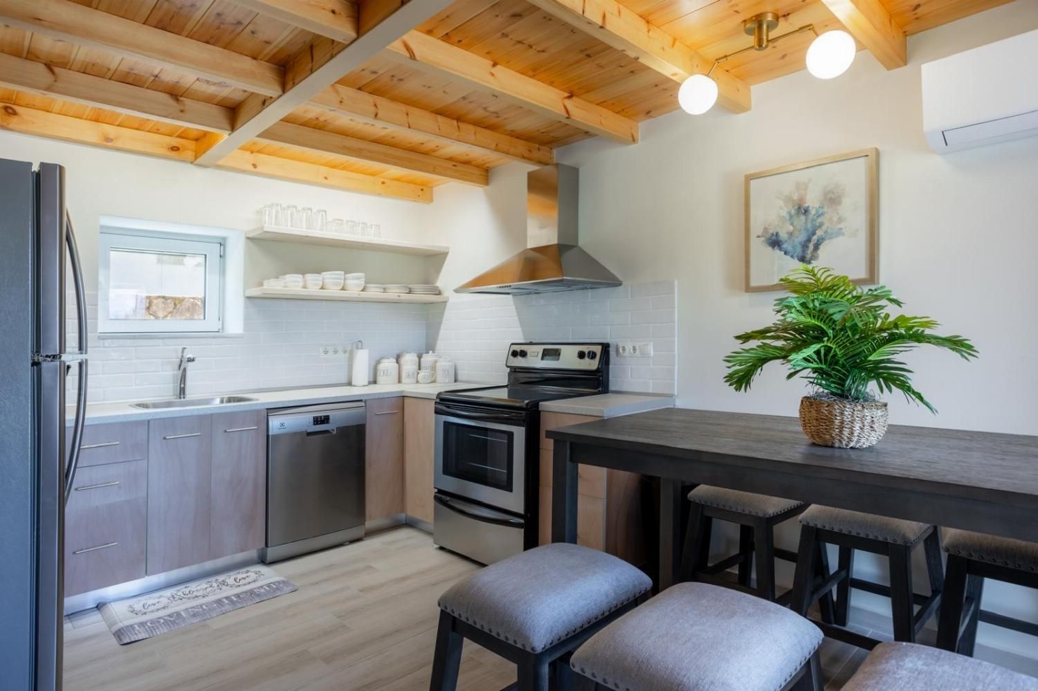 Een moderne keuken met houten balken, een fornuis, een gootsteen en een eethoek met krukken.