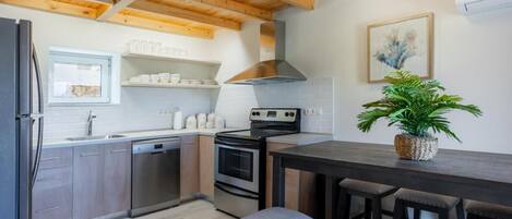 Une cuisine moderne avec des poutres en bois, une cuisinière, un évier et un coin repas équipé de tabourets.