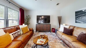 A living room with two leather sofas, a coffee table with magazines, a television, and a cabinet. - *NEW* Hullabaloo Hangout - 1.1 miles to Kyle Field! (College Station)
