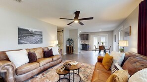 A spacious living room with a brown leather sofa, a coffee table, and a dining area in the background. - *NEW* Hullabaloo Hangout - 1.1 miles to Kyle Field! (College Station)