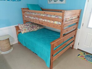 A bunk bed with a teal bedspread and patterned pillows. - Canal Front Home on sought out street - Unique, Cozy and Ready for YOU! (Ocean Isle Beach)