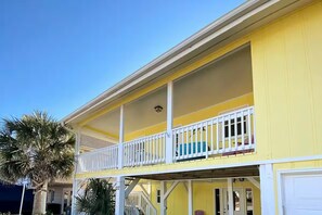 A two-story yellow building with a balcony on the upper floor. - Canal Front Home on sought out street - Unique, Cozy and Ready for YOU! (Ocean Isle Beach)