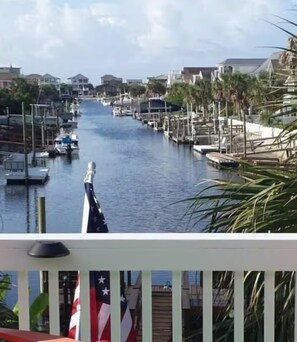 A marina with boats docked, a clear sky, and a view of houses and palm trees. - Canal Front Home on sought out street - Unique, Cozy and Ready for YOU! (Ocean Isle Beach)