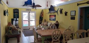A dining area with a table and chairs, a television, and a door leading outside. - Canal Front Home on sought out street - Unique, Cozy and Ready for YOU! (Ocean Isle Beach)