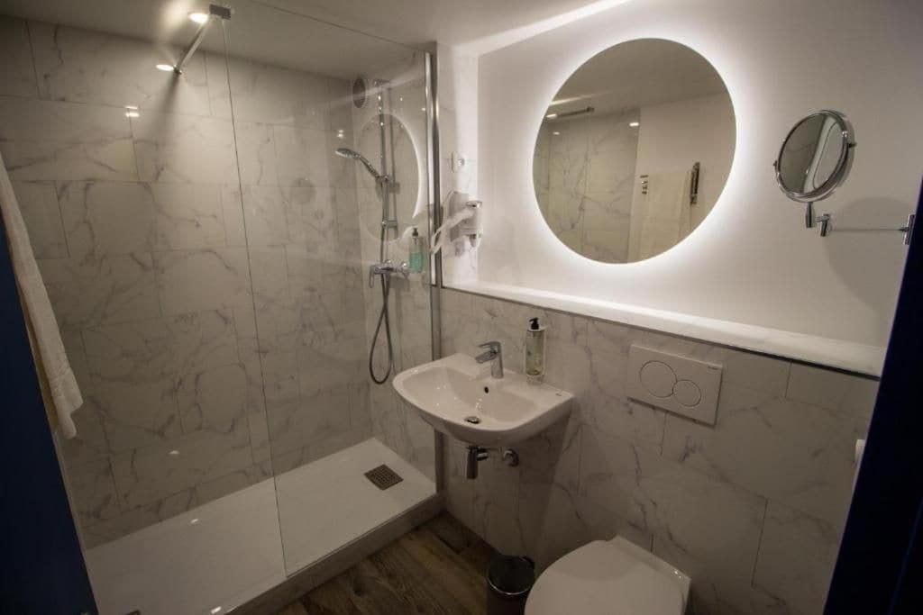 Een moderne badkamer met een douchecabine van glas, een wastafel met spiegel en een toilet.
