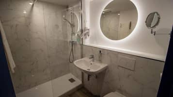 Een moderne badkamer met een douchecabine van glas, een wastafel met spiegel en een toilet.