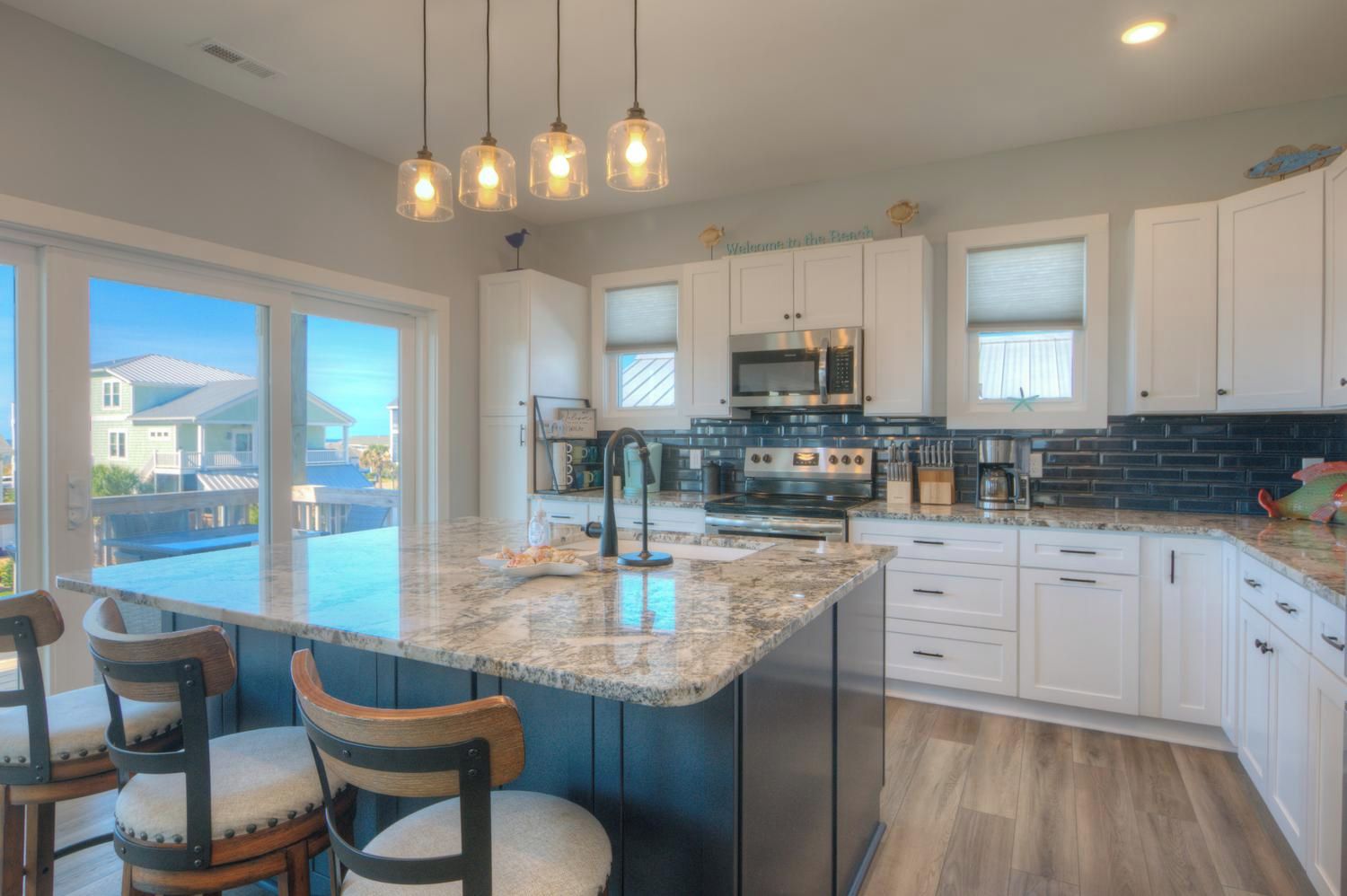 A modern kitchen with a large island, stainless steel appliances, and a view of the outside.