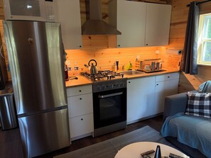 Cocina compacta con refrigerador de acero inoxidable, estufa a gas y horno empotrado.