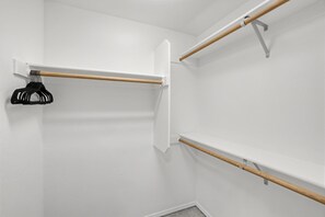 A corner of a room with white walls and a wooden closet rod with a black garment hanging on it. - Single-Level Beaverton Home | Sunroom & Garage (Beaverton)