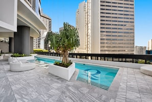 Uma área de piscina no terraço com design moderno, incluindo piscina, assentos de descanso e uma grande árvore.