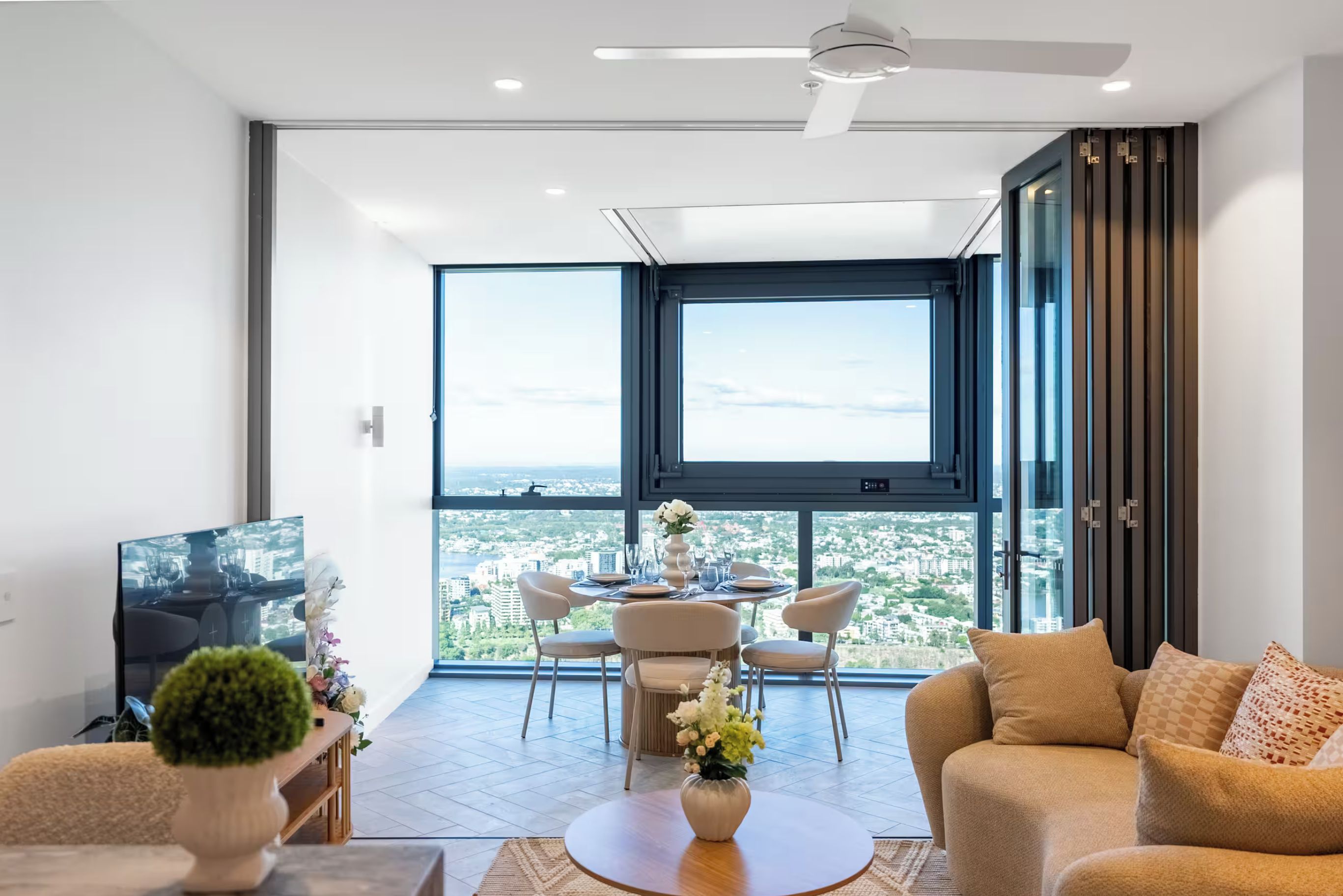 Un salon moderne avec un coin repas, de grandes fenêtres et une vue sur la ville.