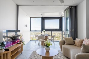 A modern living room with a large window, a dining area, and a television. - Crown's Jewel - Lv 51 Skybound Sanctuary on Casino (Brisbane City)