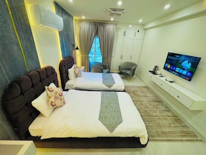 A hotel room with two beds, a TV, a wardrobe, and a window with curtains.