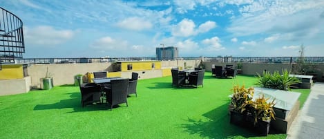 Una terraza en la azotea con césped artificial, mobiliario de exterior y plantas en macetas.