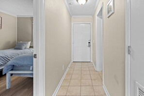 A narrow hallway with a bed on the left and a door at the end. - Coastal Retreat at Admirals Row (Hilton Head Island)
