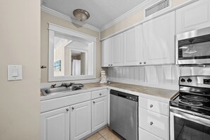 A kitchen with white cabinets, stainless steel appliances, and a dishwasher. - Coastal Retreat at Admirals Row (Hilton Head Island)