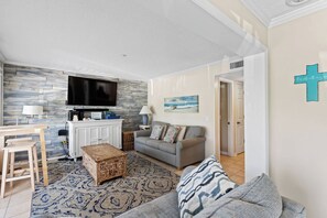 Ein Wohnzimmer mit Fernseher, Sofa und einem Kreuz an der Wand.