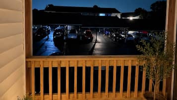 A wooden deck with a view of a parking area at dusk.