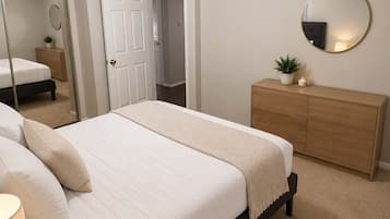 A bedroom with a bed, a dresser, a mirror, a ceiling fan, and a door leading to another room.