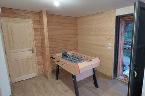 A room with a wooden door, a wooden wall, and a foosball table. - Large 4-Star Chalet at Balné ô Sancy (Chastreix)