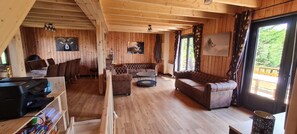 A wooden interior with a sofa, a round coffee table, and a printer on a shelf. - Large 4-Star Chalet at Balné ô Sancy (Chastreix)