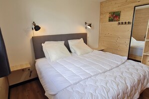 A bed with white bedding and two bedside lamps, a wooden headboard, and a wall-mounted picture. - Large 4-Star Chalet at Balné ô Sancy (Chastreix)