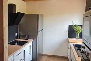 Eine kompakte Küche mit Einbauofen, Kühlschrank und Toaster.