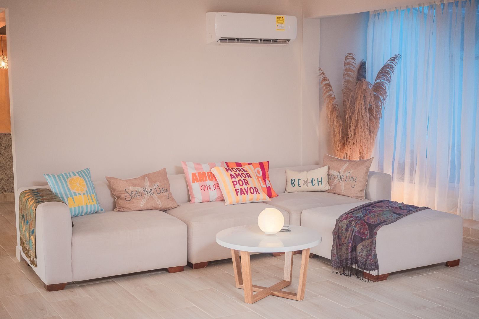 A living room with a beige sofa, a round coffee table, and decorative pillows.