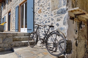 A bicycle parked against a stone wall with a wooden beam and a metal rack. - Country House “Chez Julia” with Shared Terrace, Private Garden, and Wi-Fi (Cazavet)