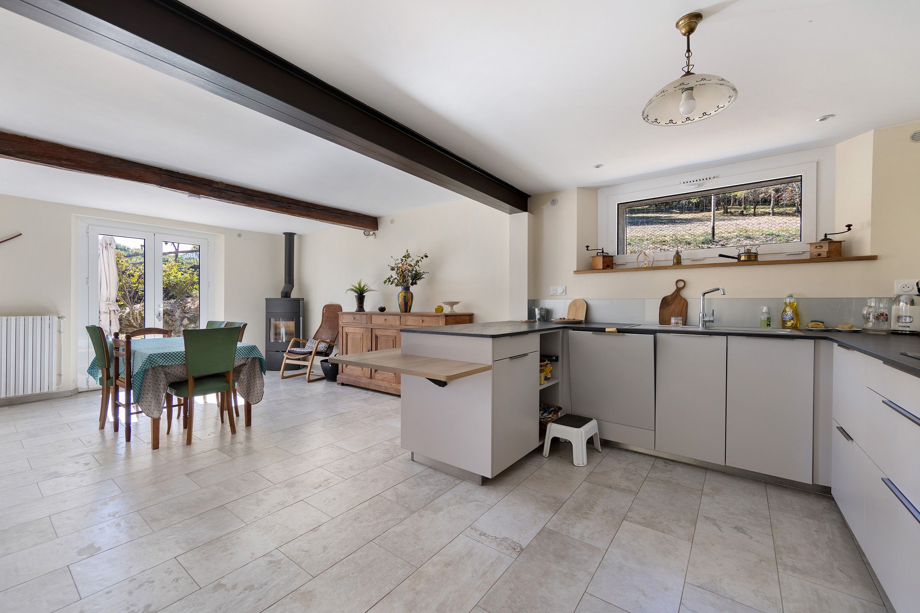 A modern kitchen with a central island, built-in appliances, and a dining area with a view.