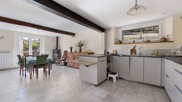 A modern kitchen with a central island, built-in appliances, and a dining area with a view.