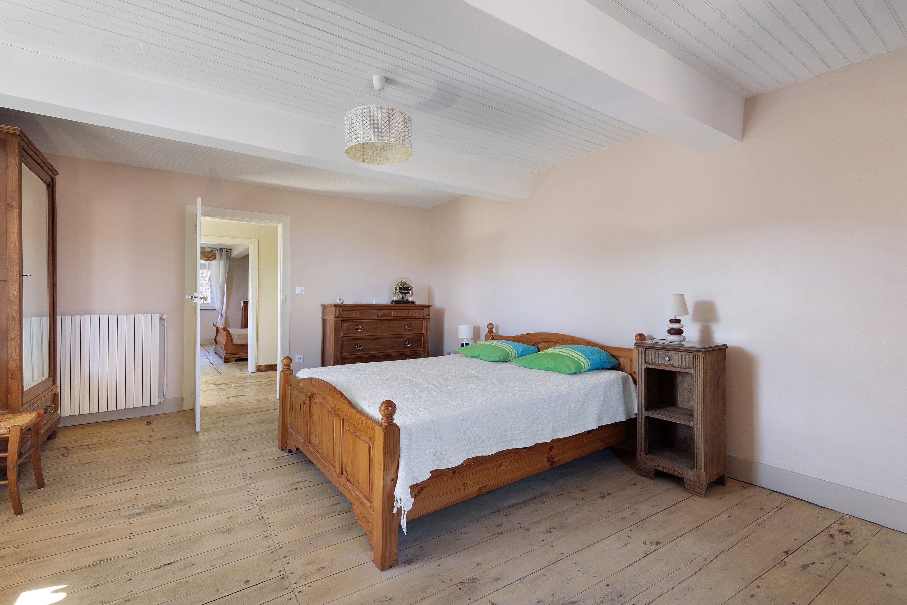 Une chambre à coucher avec un lit en bois, une table de chevet, une commode et un radiateur.