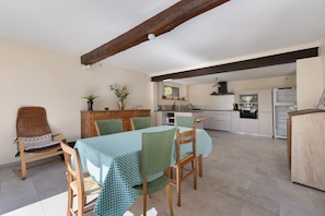 A dining area with a table set for four, surrounded by chairs, a wooden bench, and a small side table with a vase. - Country House “Chez Julia” with Shared Terrace, Private Garden, and Wi-Fi (Cazavet)