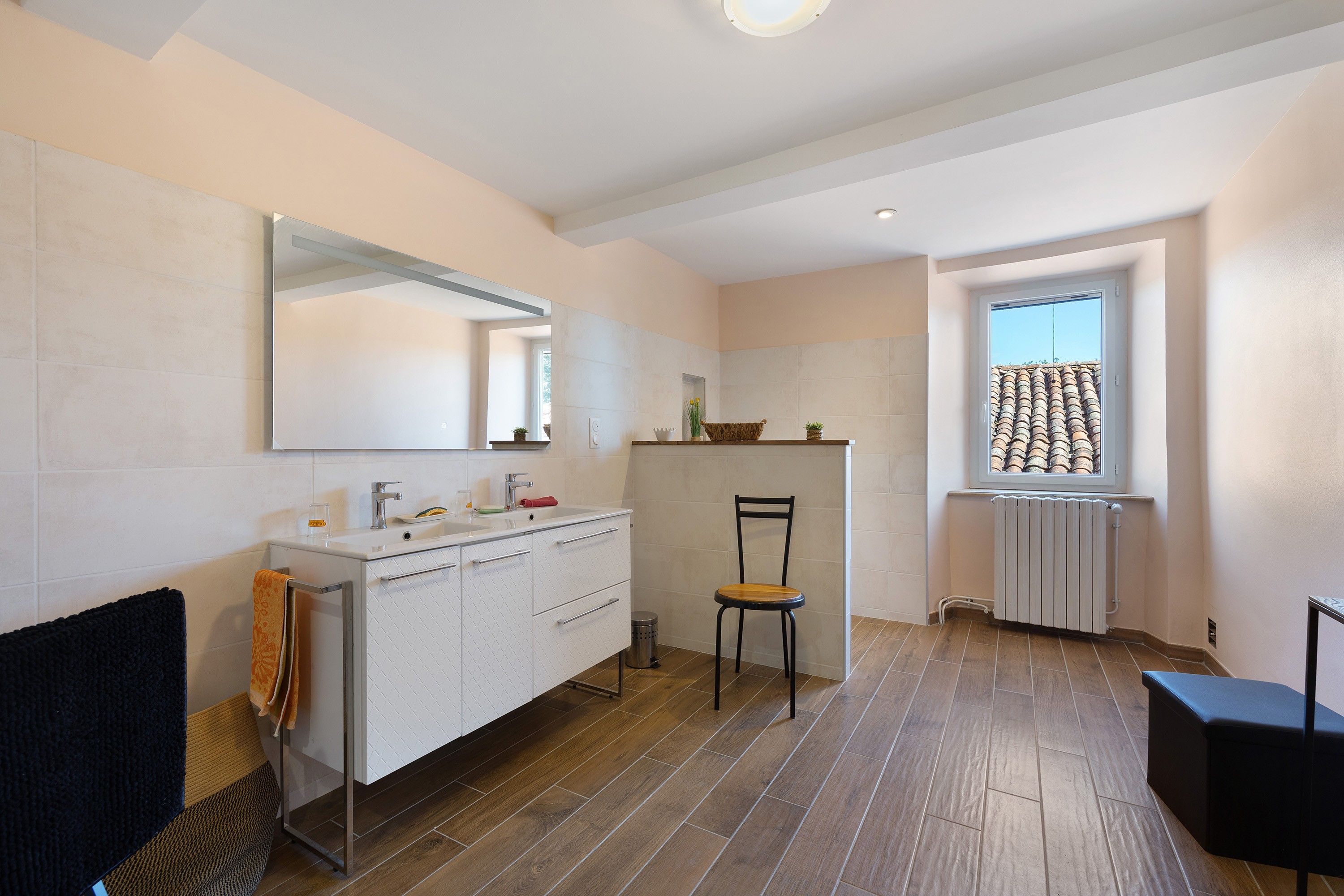 Un baño moderno con un espejo grande, un lavabo y una silla.