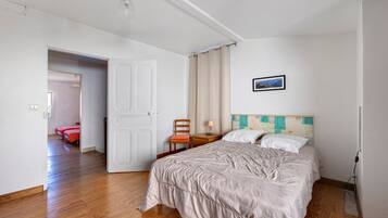 Habitación de hotel con una cama, una silla, una mesita de noche, una lámpara y un cuadro en la pared.