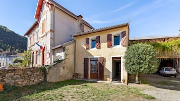 A two-story building with a stone wall and a wooden door.
