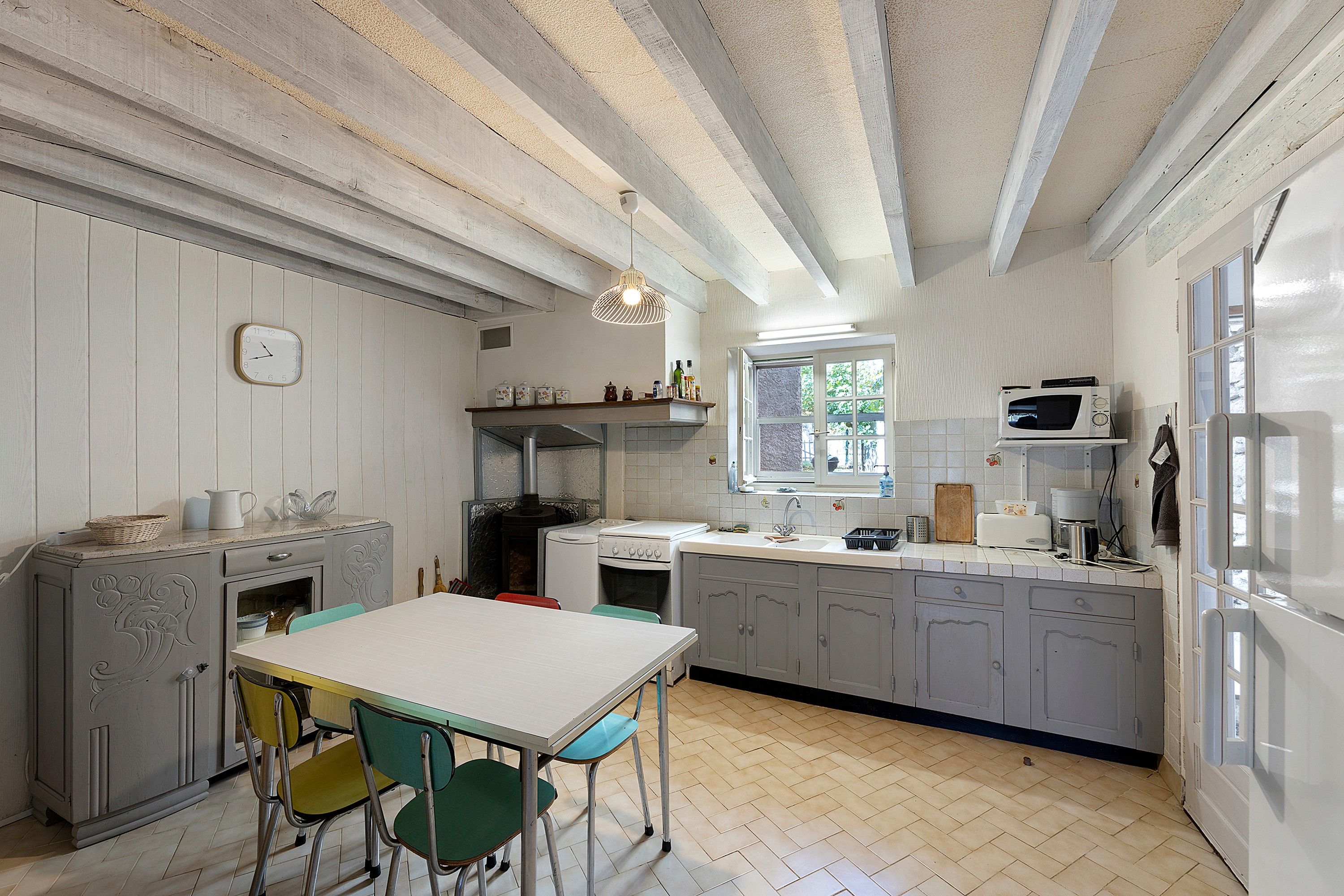 A kitchen with a white table, green chairs, a stove, a microwave, and a window.