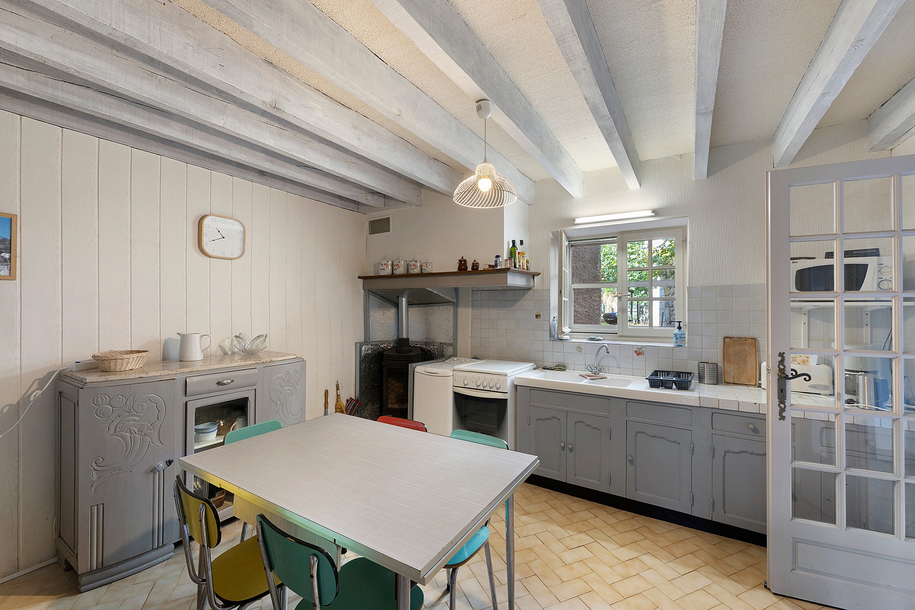 A kitchen with a dining table, chairs, a stove, and a window.
