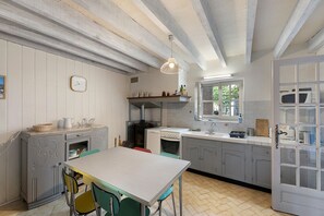 A kitchen with a dining table, chairs, a stove, and a window. - Holiday Home “Chez You” with Mountain View, Private Terrace and Garden (Cazavet)