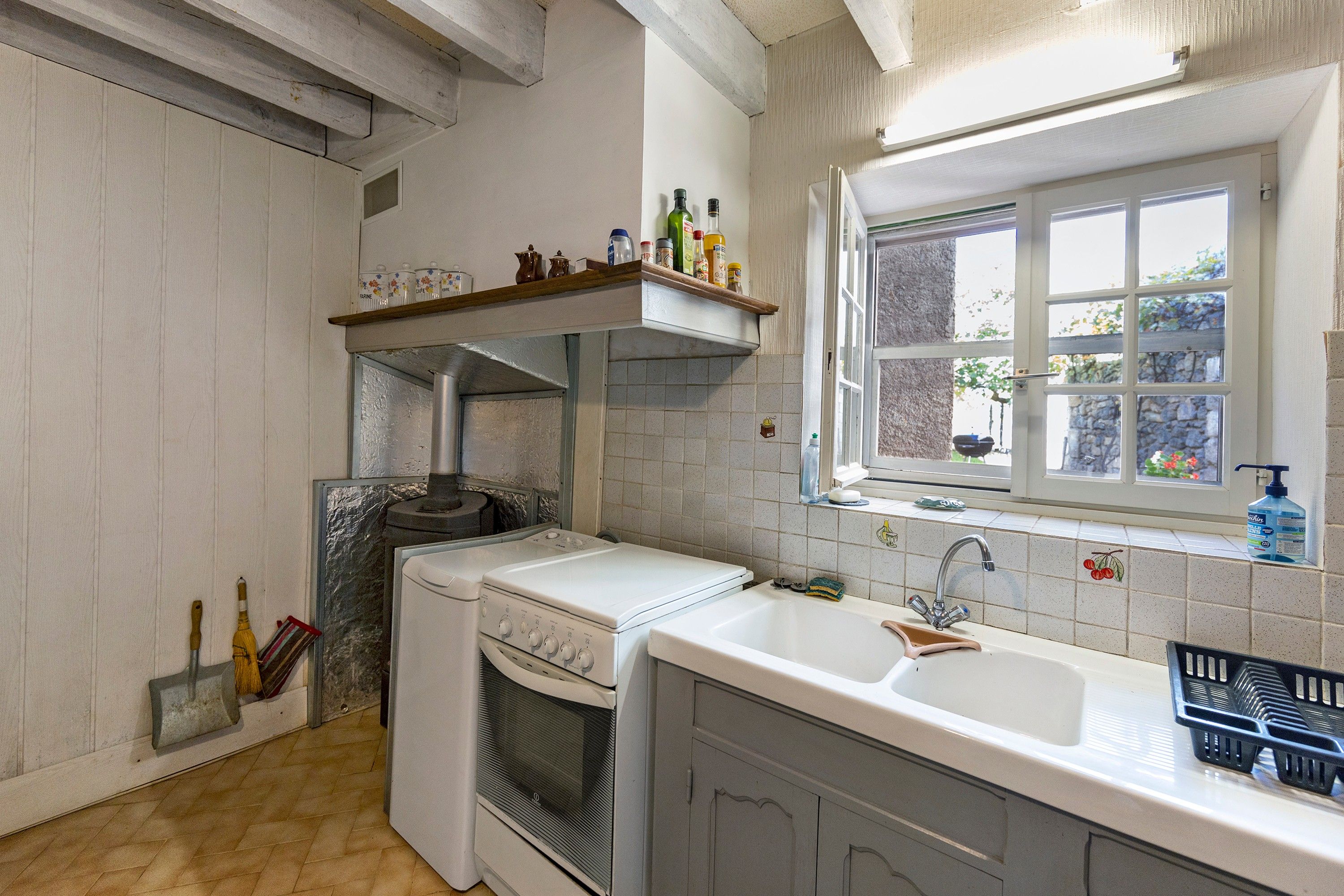A kitchen with a built-in oven, a sink, and a window with a view of greenery.
